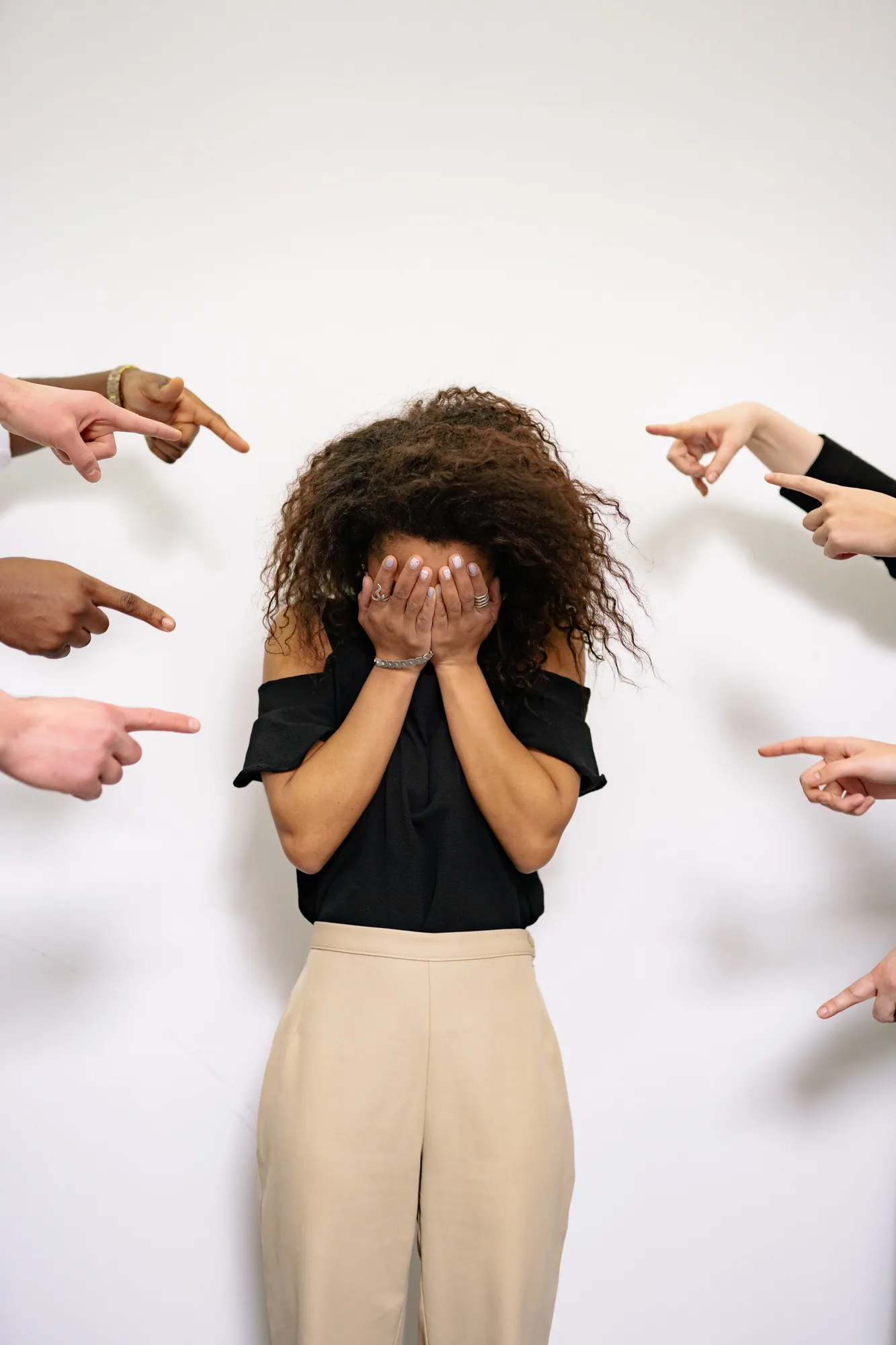 Distressed employee covering her face as colleagues point at her